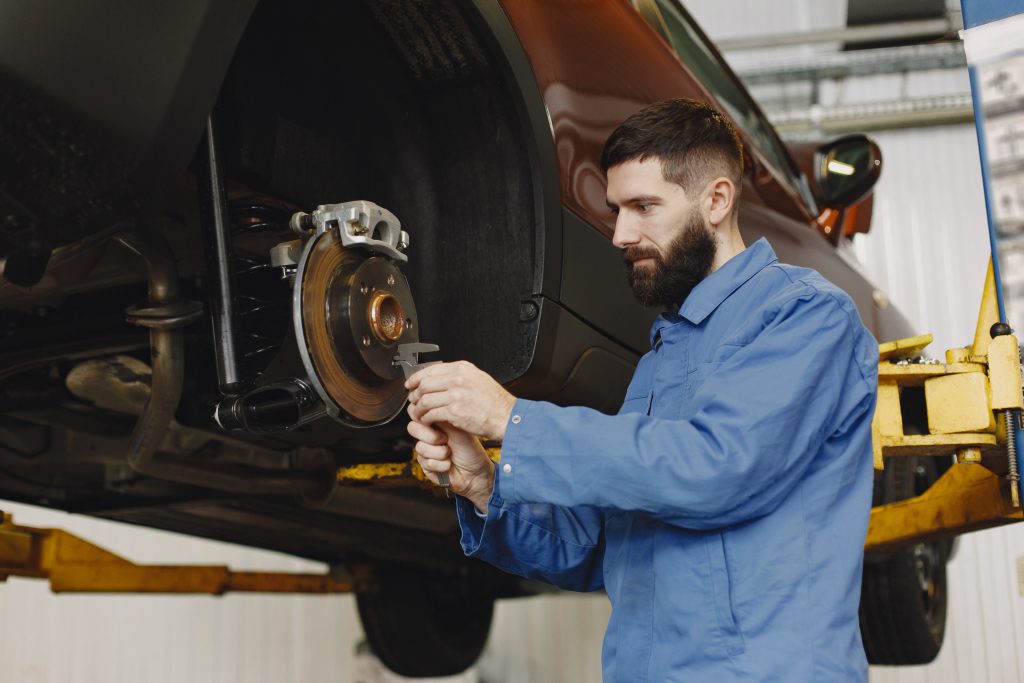 Man replaces wheel in car in garage on hoist